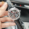 Close-up shot of a hand holding the wheel inspired skeleton mechanical watch with a black leather strap