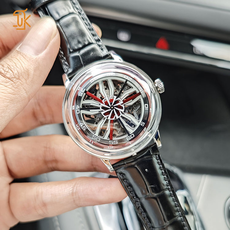 Close-up shot of a hand holding the wheel inspired skeleton mechanical watch with a black leather strap