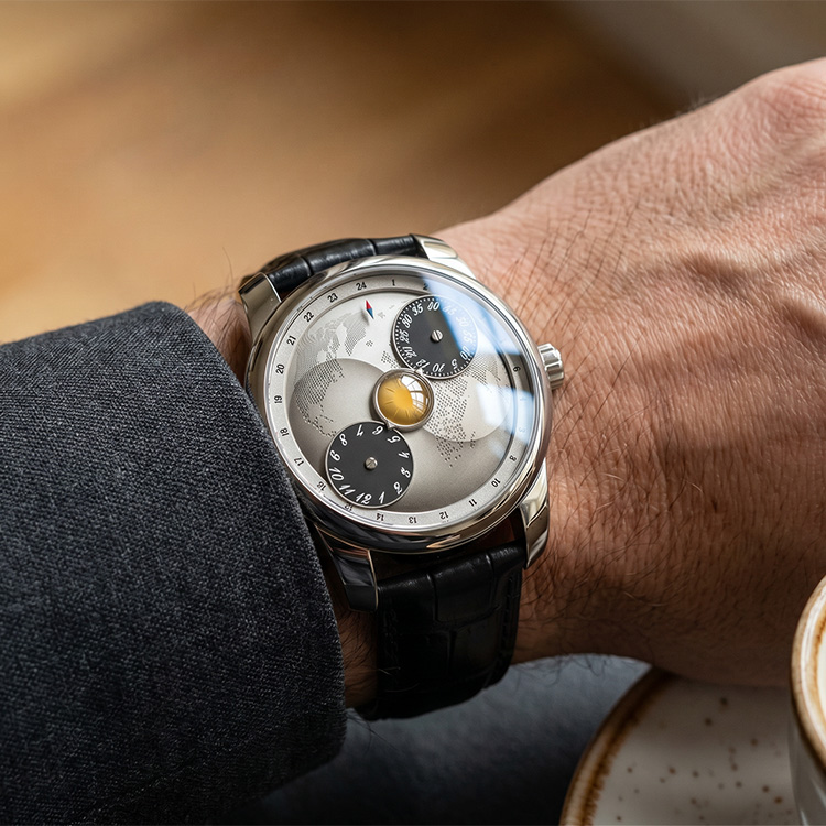 On-wrist view of the moonphase wandering hour mechanical watch with a silver dial and black leather strap